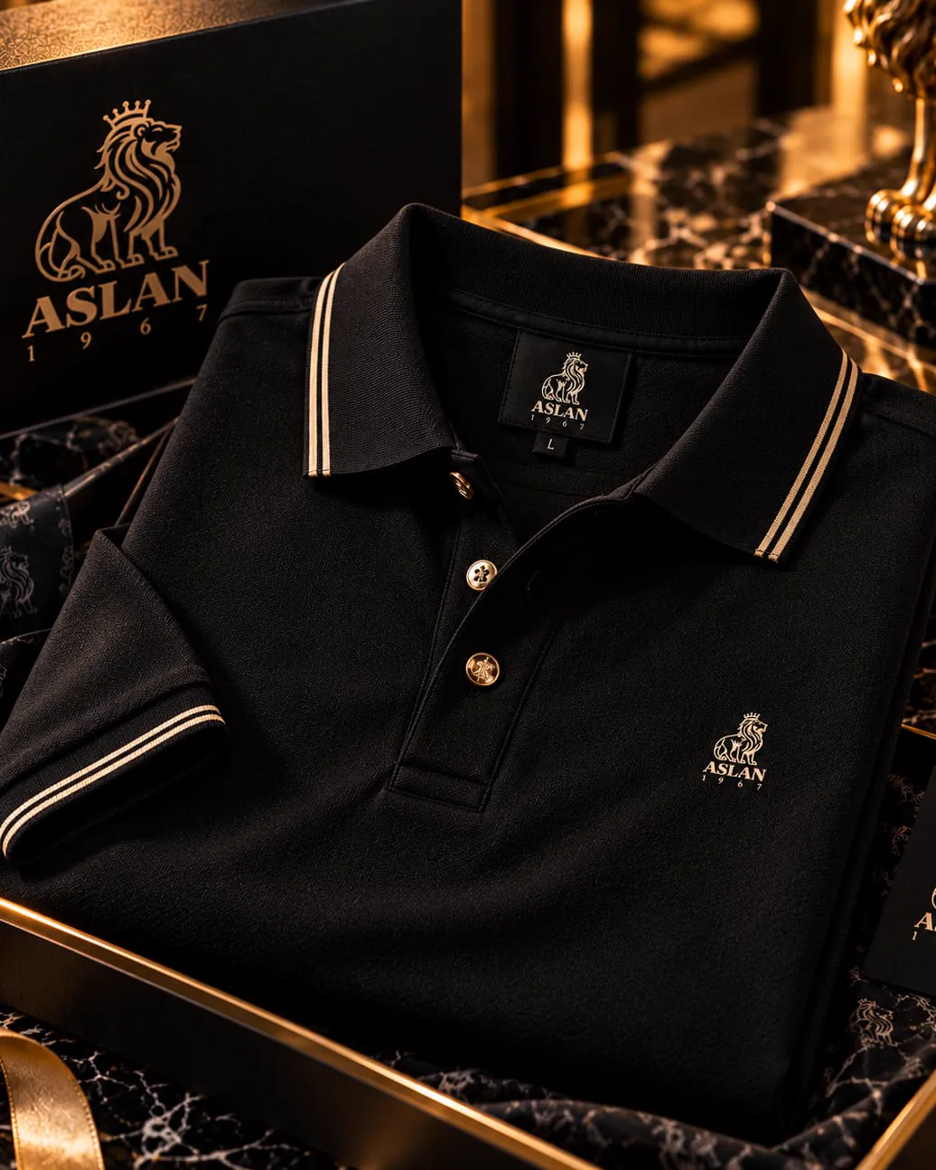 Polo noir ASLAN 1967 à liserés crème et boutons dorés, dans son coffret.